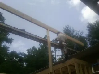 Carpenter setting a ridge beam over a new addition frame — Ice Dam Removal by Roofing Brothers in Bearcreek