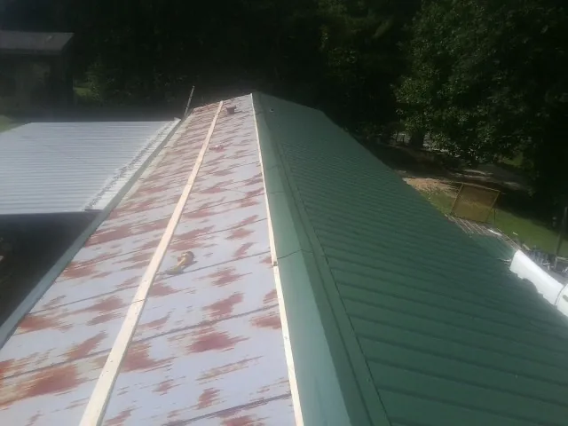 Old rusted panels beside newly installed green metal roofing — Wind Damage Roof Repair by Roofing Brothers in Bearcreek