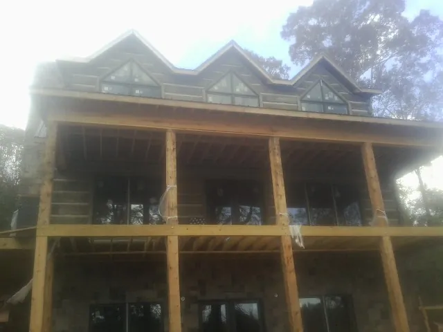 Dormers and porch framing on a large log home under construction — Roof Coating work by our crew in Bearcreek