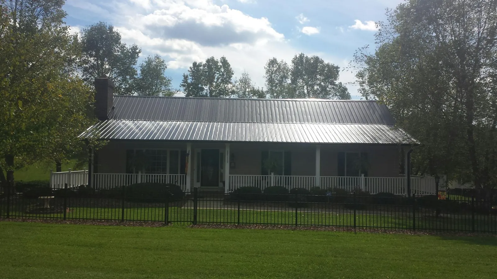 Gray metal roof on a brick ranch with a full width front porch — Gutter Guard Installation work by our crew in Bearcreek