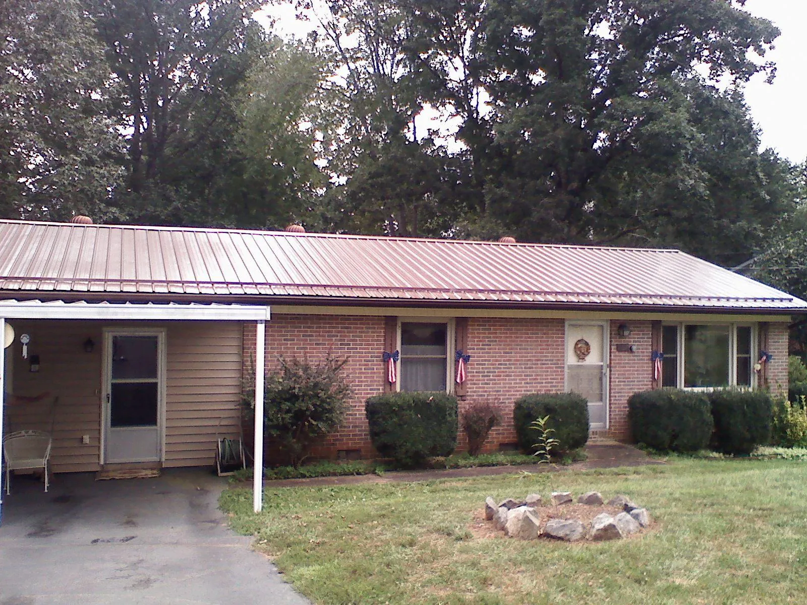 Bronze metal roof and carport on a brick ranch home — Roof Repair work by our crew in Bearcreek