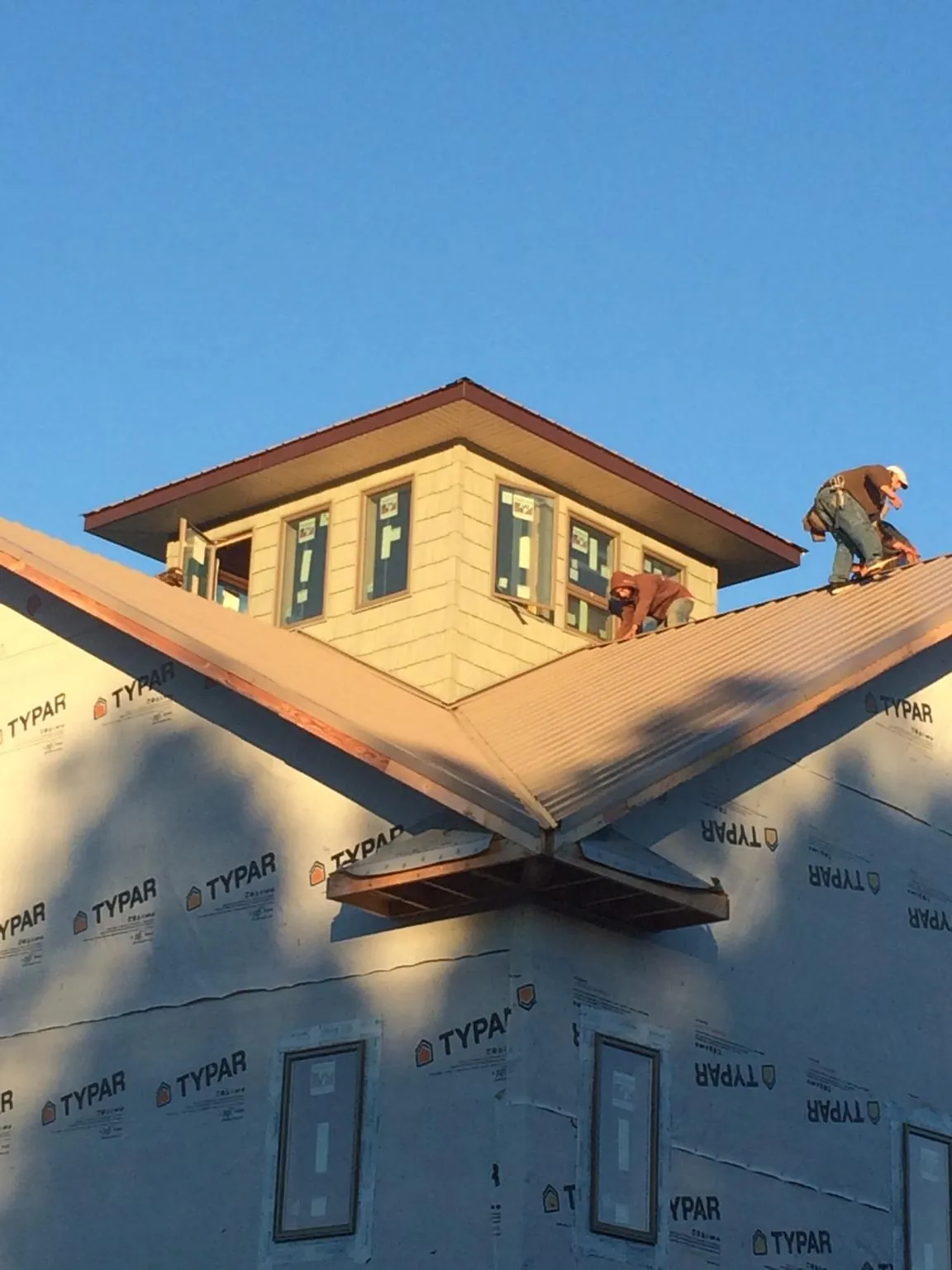 Roofers working around a rooftop cupola on a new metal roof at sunset — Roof Waterproofing in Bearcreek by Roofing Brothers
